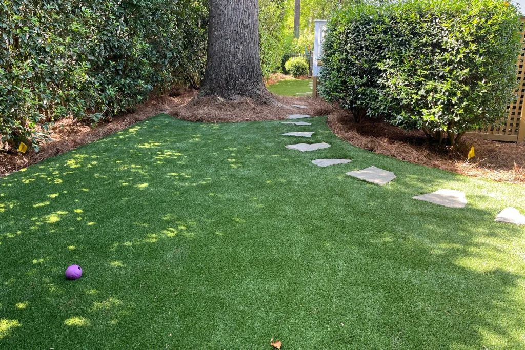 lush, green artificial turf lawn next to a natural stone flagstone pathway